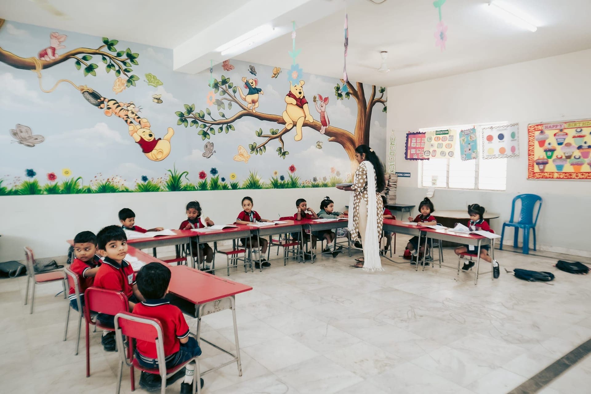 A teacher with young students in a bright, mural-decorated classroom